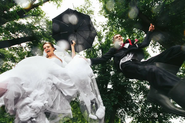 Bruden och brudgummen hoppa som en barn i pooler — Stockfoto