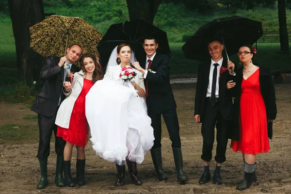 Newyweds, brudtärnor och marskalkar pose under paraply i gumbo — Stockfoto