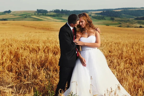 Groom tient l'épaule tendre d'une jolie mariée debout sur la fi — Photo