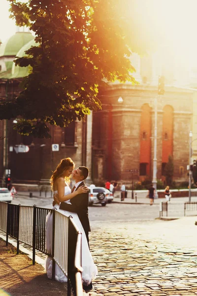 Sposi in piedi su una vecchia piazza della città in una giornata di sole — Foto Stock