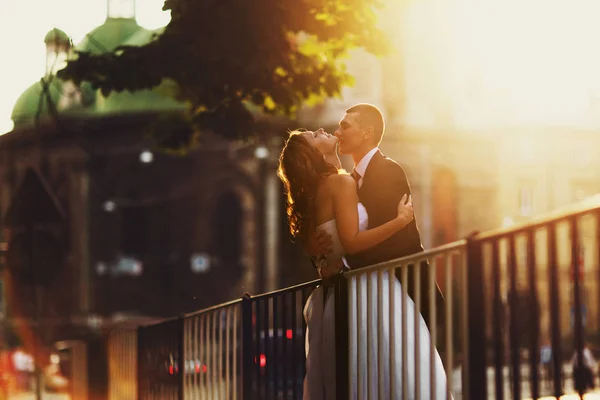 Sun illuminates a kissing wedding couple somewhwere on the stree — Stock Photo, Image
