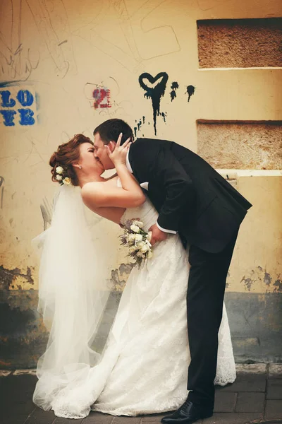 Bräutigam beugt Braut vor Wand mit Blac — Stockfoto