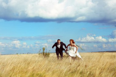 Gelin ve damat bir parlak rüzgara karşı araziyi çalıştırmak