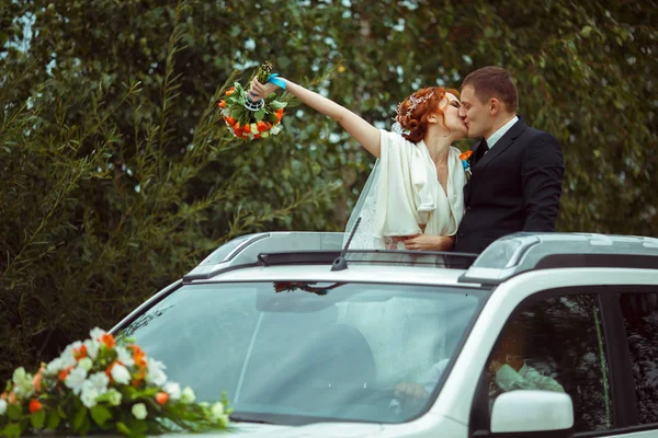 Just married kiss standing in the hatchway of a car — Stock Photo, Image