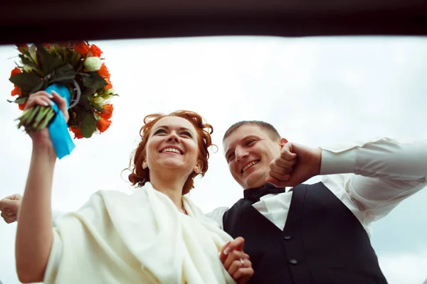 Una vista dal basso su una sposa sorridente e lo sposo in piedi in un cappello — Foto Stock