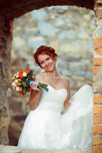 Sorrisi da sposa in piedi in una finestra del vecchio castello in rovina — Foto Stock