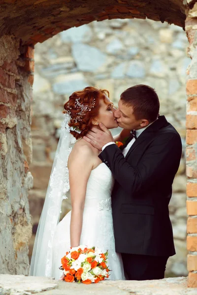 Ein leidenschaftlicher Kuss von Frischvermählten, die in einem großen Backsteinfenster stehen — Stockfoto