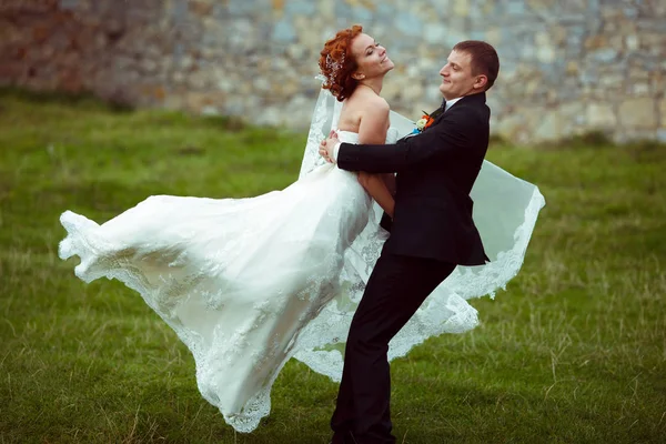Braut lächelt, während ein Bräutigam sie herumwirbelt — Stockfoto