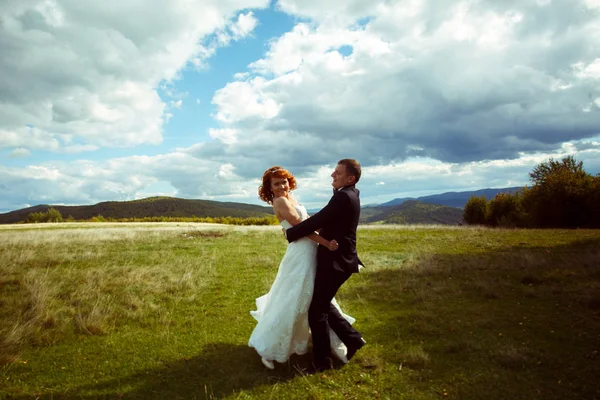 Feliz boda pareja danza en la colina bajo un profundo blye cielo — Foto de Stock