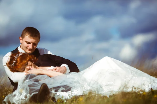 Feliz novia se encuentra en las rodillas del novio bajo un cielo nublado — Foto de Stock