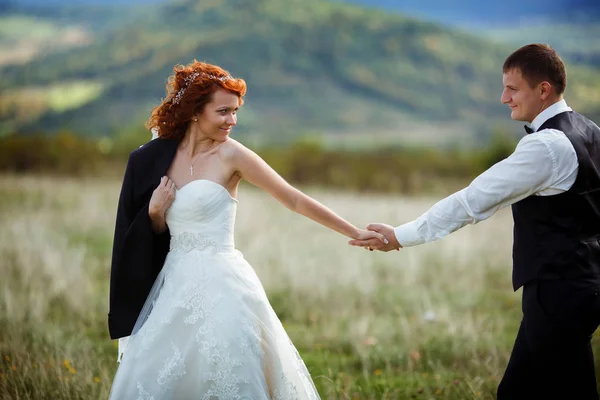 Vőlegény következik a menyasszony fogta a kezét valahol át a ruhát hegyi — Stock Fotó