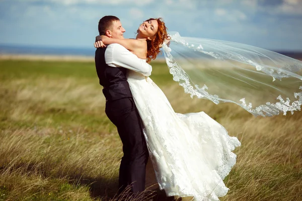 El viento sopla el velo de la novia mientras el novio la gira — Foto de Stock