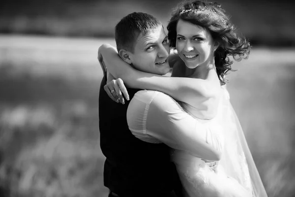 Sposa ang sposo guardare gioioso abbraccio da qualche parte sul campo — Foto Stock