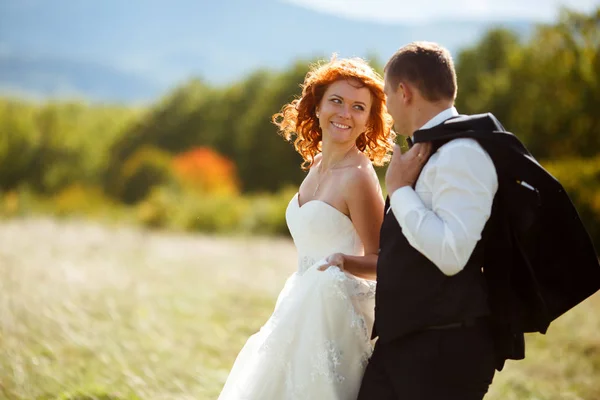 Noiva olha com amor para um noivo caminhando ao longo do campo — Fotografia de Stock