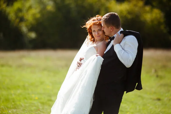 Splendida sposa si appoggia a uno sposo con la schiena mentre lui bacia lui — Foto Stock