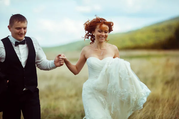 El pelo rizado de la novia se mezcla mientras camina con un novio a través de la — Foto de Stock