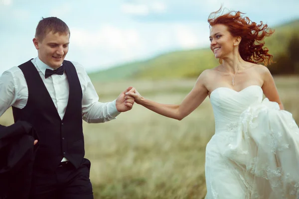 Bride smiles looking at a groom and holding his hand — Stock Photo, Image