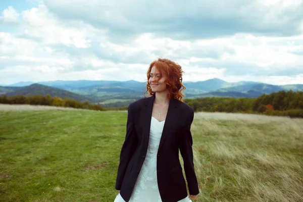 Mariée sourit debout sur le terrain dans la veste du marié avec une grande — Photo