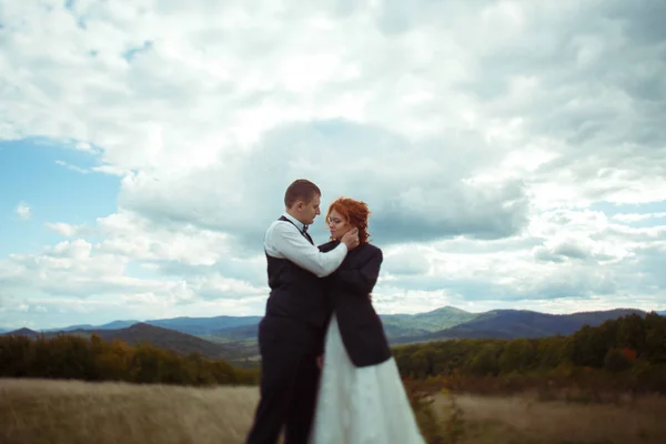 Grandes nubes blancas vuelan sobre un recién casados de pie en el campo — Foto de Stock