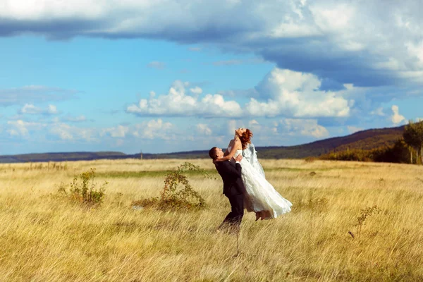 Brudgummen stiger bruden upp stående på fältet under en djupblå himmel — Stockfoto