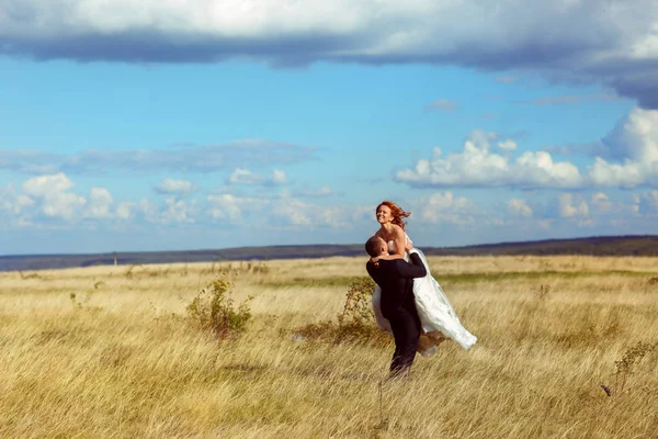 Groom tient mariée debout dans une herbe sous le ciel bleu — Photo