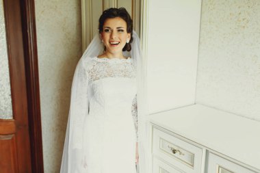 Gelin geniş ayakta beyaz bir gardırop gülüyor.