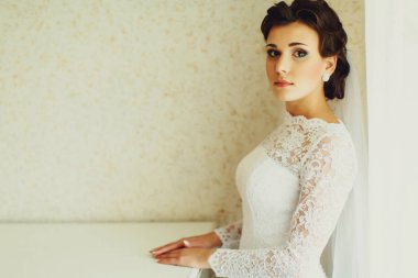 Esmer gelin beyaz bir duvar düz duruyor