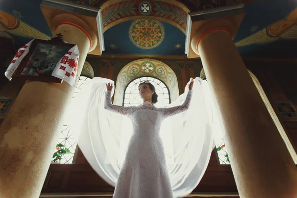 Bruid heeft haar sluier omhoog staande aan de voorkant van een venster in chu — Stockfoto