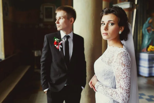 Νύφη στέκεται ίσια, ενώ γαμπρός κοιτάζει έξω από το παράθυρο — Φωτογραφία Αρχείου