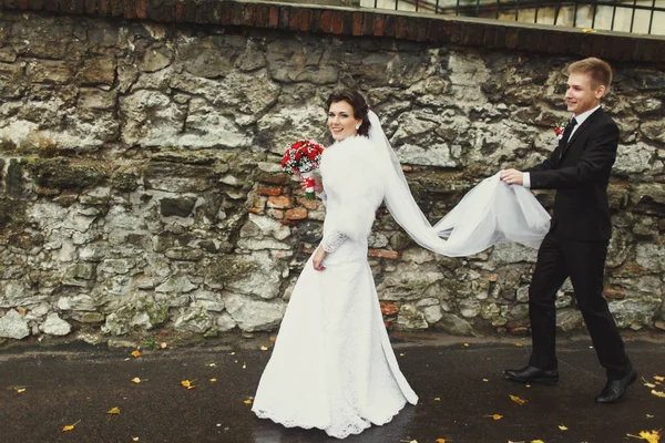 Menyasszony és a vőlegény szórakozni, séta az utcán egy őszi után — Stock Fotó