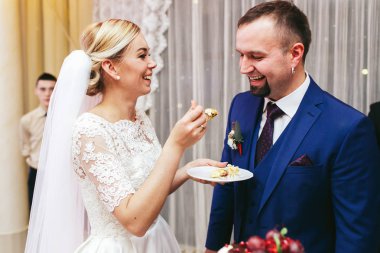 Gelin düğün pastası bir kaşıkla damadın ağız için yükselir. 
