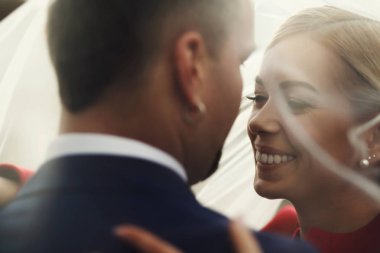 Güzel gelin gülümsüyor geniş yaslanmış bir peçe altında bir damat için 