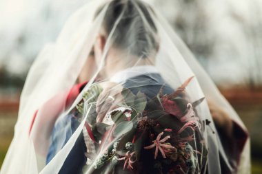 Geri und sarılmak iken gelin damadın üzerinde bir düğün buket tutar