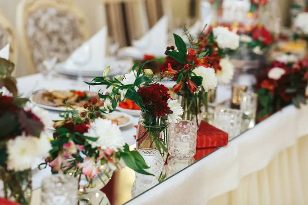 Chrysanthèmes rouges et blancs se tiennent dans de petits vases en verre sur un di — Photo