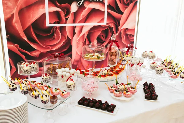 Mesa con chocolates y dulces decorados en col rosa y blanca — Foto de Stock