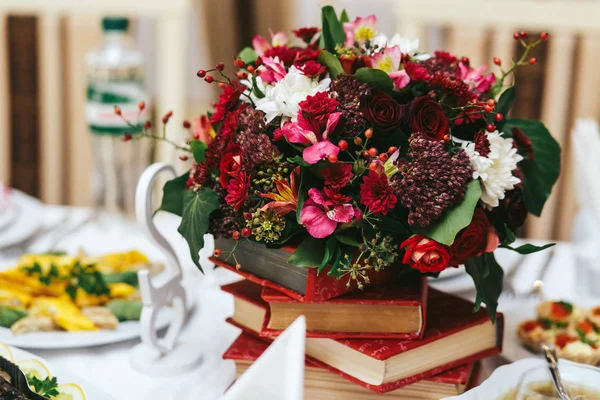 丰富的秋天花束站在红色的书。餐桌装饰 — 图库照片