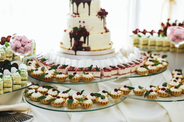 Piccoli cupcake di formaggio con bacche rosse poggiano su un buffet di vetro — Foto Stock