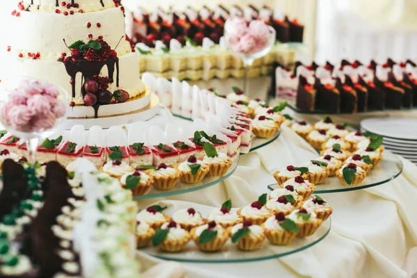 Pasteles con frutas y menta rodean un pastel de bodas — Foto de Stock