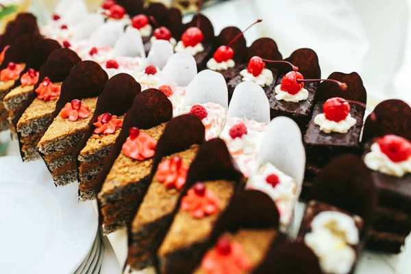 Beyaz, siyah ve kahverengi Pastalar kırmızı meyveler ile dekore edilmiş stand — Stok fotoğraf