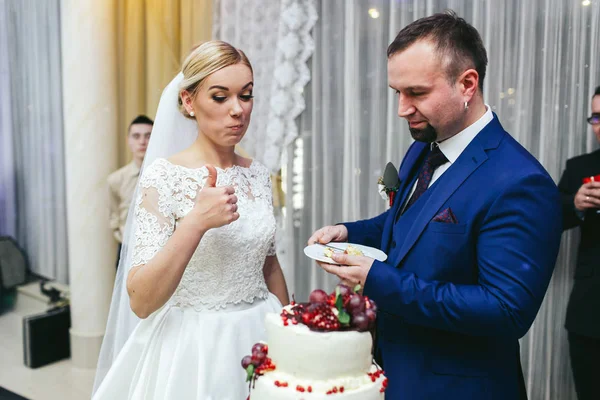 Забавная невеста поднимает большой палец после того, как попробовала свадебный торт — стоковое фото