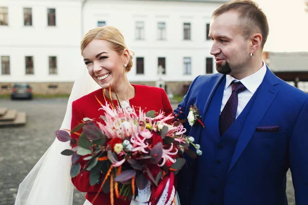 Bella sposa bionda sorride in piedi con uno sposo e tenendo una b — Foto Stock