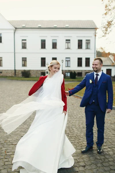 Sposo cerca di tenere la mano di una sposa mentre il vento soffia il suo velo awa — Foto Stock