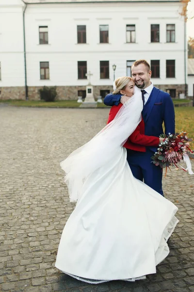 Sposo abbraccia una sposa mentre velo avvolge il suo viso — Foto Stock