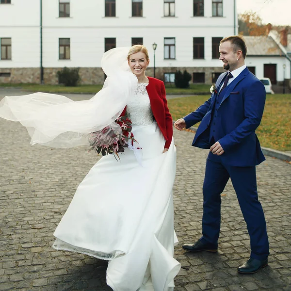 Bruid wervelingen rond staande achter een bruidegom in blauwe pak — Stockfoto