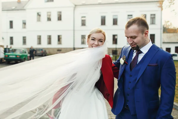 A noiva sorri com um véu virado em volta do pescoço, de pé atrás — Fotografia de Stock