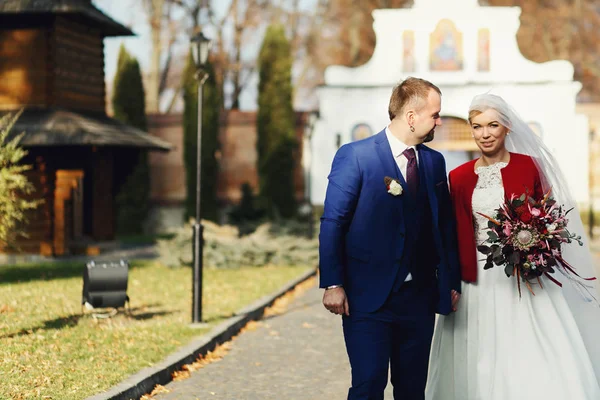 Elegante coppia di sposi cammina lungo il percorso dai vecchi cancelli — Foto Stock