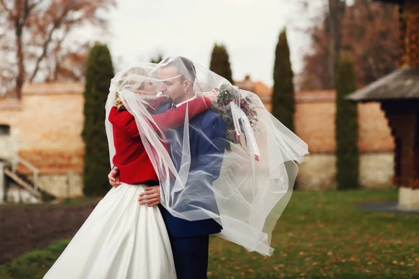 Um momento lindo entre o casal de casamento de pé sob um véu b — Fotografia de Stock