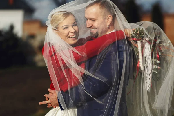 Sposa e sposo sorridono lucido in piedi sotto un velo — Foto Stock