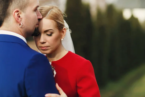 Sposo baci sposa fronte tenero mentre sono su un verde — Foto Stock