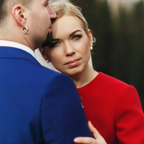 Novia se ve impresionante ser abrazado por un novio en traje azul — Foto de Stock